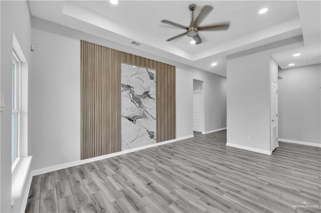 unfurnished room with recessed lighting, ceiling fan, a raised ceiling, and light wood-style flooring