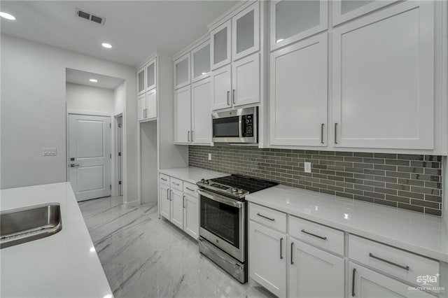 kitchen featuring visible vents, marble finish floor, appliances with stainless steel finishes, and white cabinetry