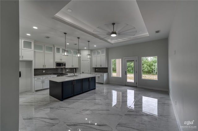 kitchen featuring ceiling fan, marble finish floor, stainless steel appliances, baseboards, and backsplash