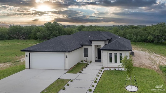 single story home featuring concrete driveway, a lawn, a shingled roof, and a garage