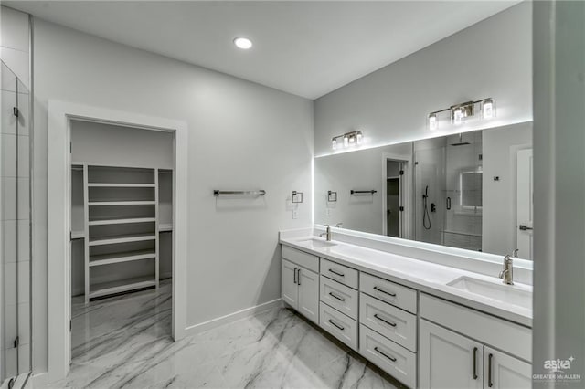 full bathroom with a walk in closet, a shower stall, a sink, and marble finish floor