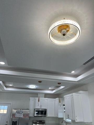 details featuring a raised ceiling, white cabinets, and stainless steel appliances