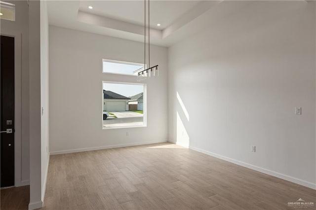 spare room featuring baseboards, a tray ceiling, wood finished floors, and recessed lighting