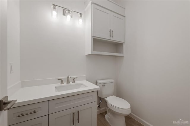 bathroom with baseboards, wood finished floors, toilet, and vanity