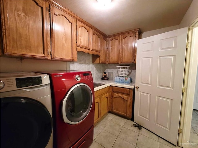 laundry area with cabinets, light tile patterned floors, and washer and clothes dryer