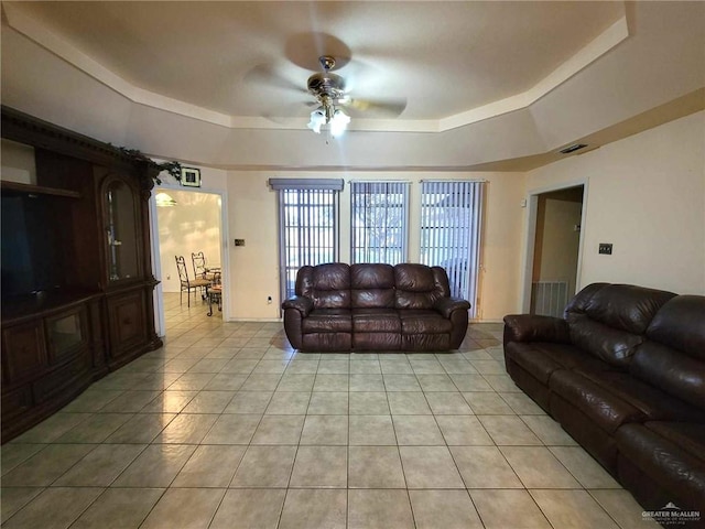 living room featuring ceiling fan, light tile patterned flooring, and a raised ceiling