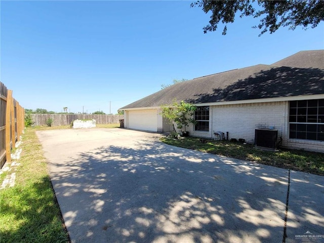 view of side of home featuring cooling unit and a garage