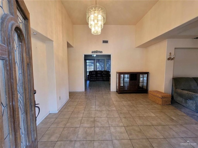 tiled entryway with a towering ceiling and an inviting chandelier