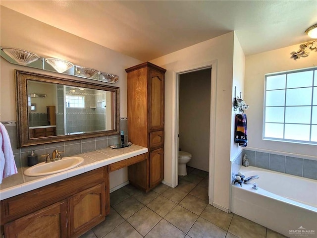 bathroom featuring tile patterned floors, vanity, toilet, and a bath