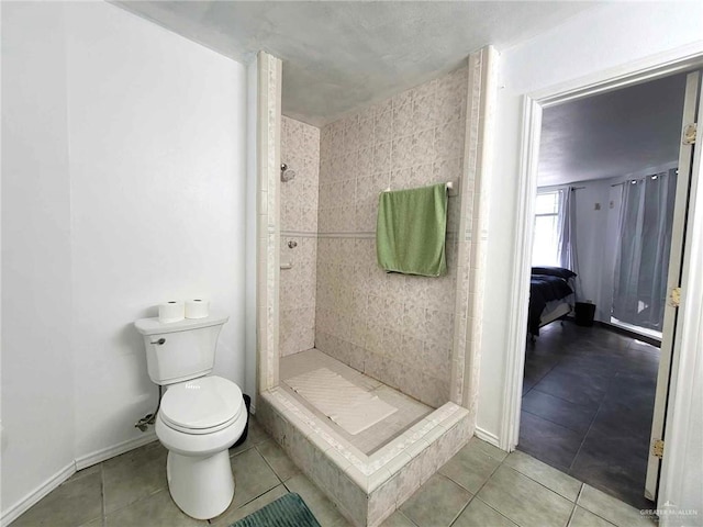 bathroom with a tile shower, tile patterned flooring, and toilet