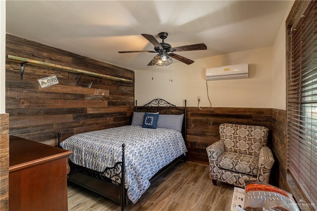 bedroom with wooden walls, ceiling fan, and a wall unit AC