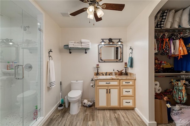 bathroom featuring wood-type flooring, vanity, toilet, and an enclosed shower