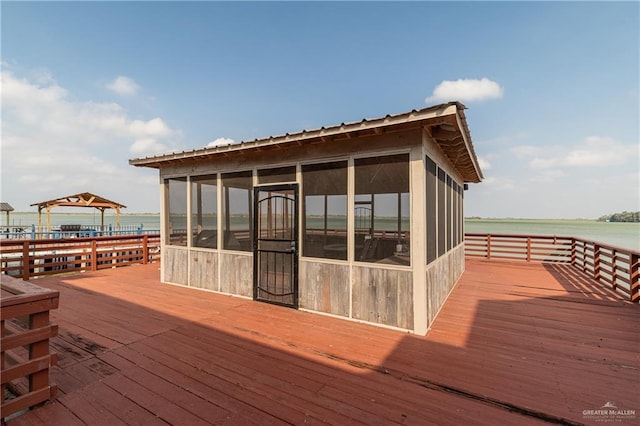 wooden deck with a sunroom, a gazebo, and a water view