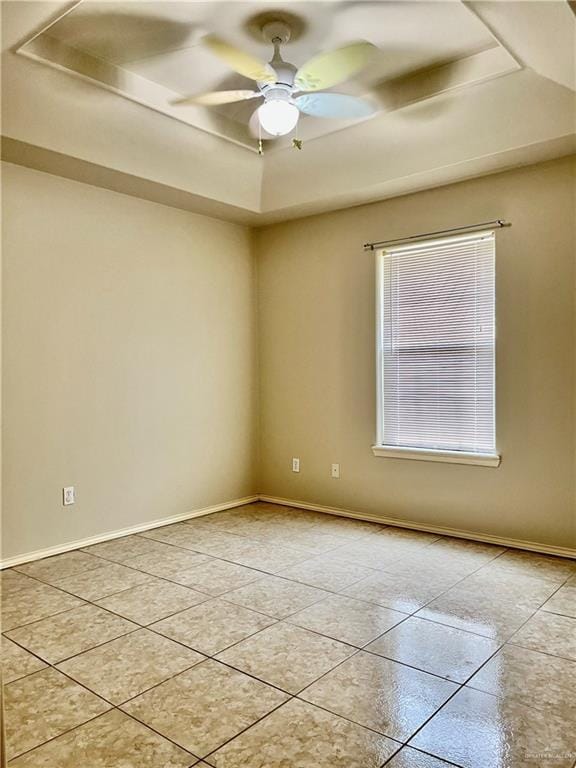 empty room with light tile patterned floors, baseboards, and a raised ceiling