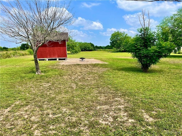 view of yard with an outdoor fire pit, an outbuilding, and a shed