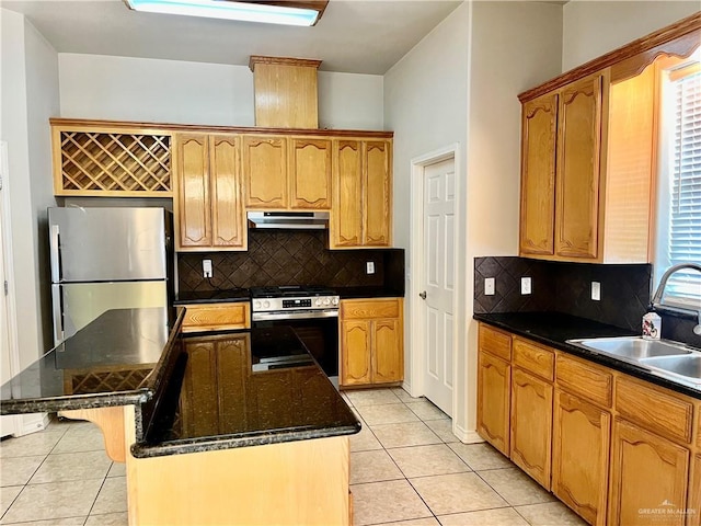 kitchen featuring under cabinet range hood, light tile patterned flooring, a sink, and appliances with stainless steel finishes