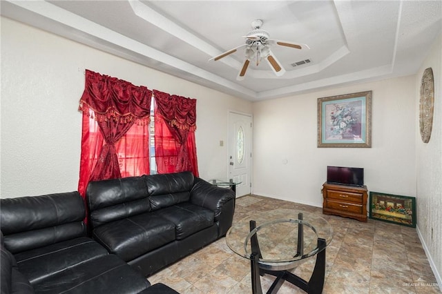 living room featuring ceiling fan and a tray ceiling