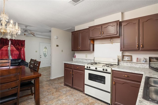 kitchen featuring hanging light fixtures, white gas range, a textured ceiling, a notable chandelier, and dark brown cabinets