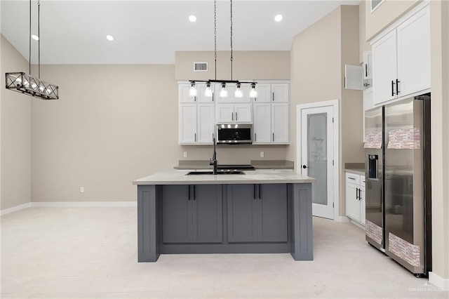 kitchen featuring a kitchen island with sink, pendant lighting, white cabinets, and stainless steel appliances