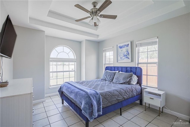 bedroom featuring a raised ceiling, baseboards, light tile patterned floors, and a ceiling fan