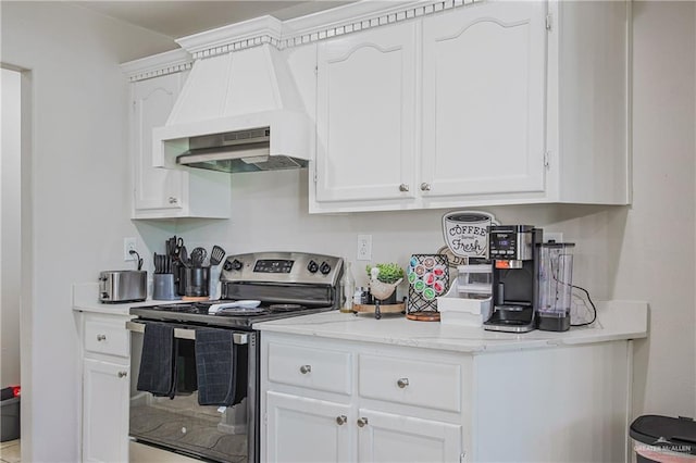 kitchen featuring stainless steel electric stove, white cabinets, premium range hood, and light stone counters