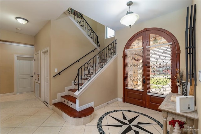 entryway featuring baseboards, arched walkways, stairs, french doors, and light tile patterned flooring