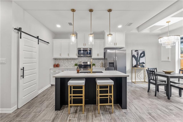 kitchen featuring a barn door, visible vents, appliances with stainless steel finishes, light countertops, and backsplash