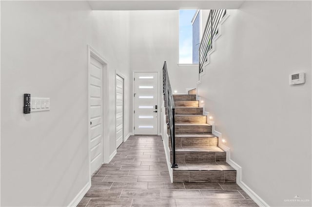 entryway featuring wood tiled floor, baseboards, and stairs