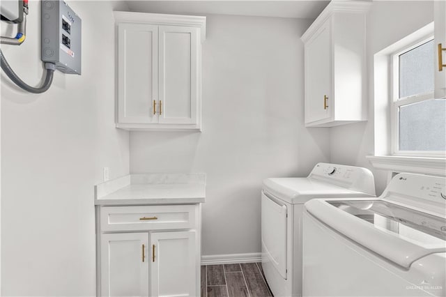 clothes washing area with cabinet space, washing machine and dryer, wood tiled floor, and baseboards