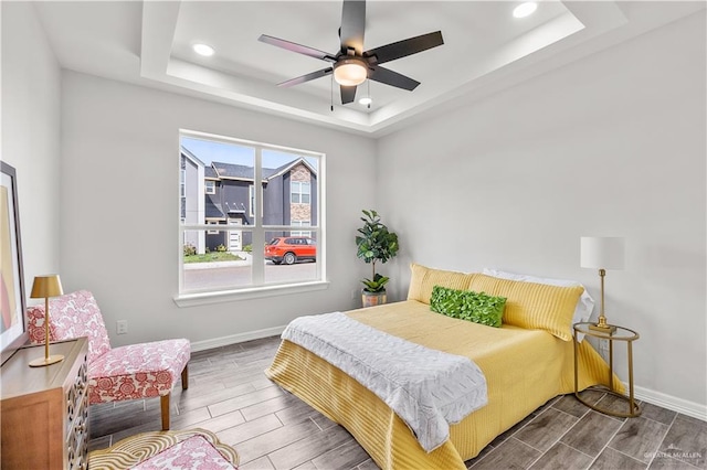 bedroom featuring recessed lighting, baseboards, a raised ceiling, and wood finish floors