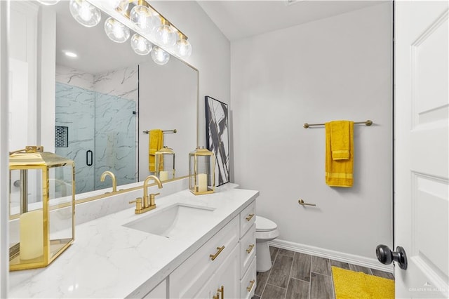 full bath featuring a marble finish shower, toilet, wood tiled floor, vanity, and baseboards