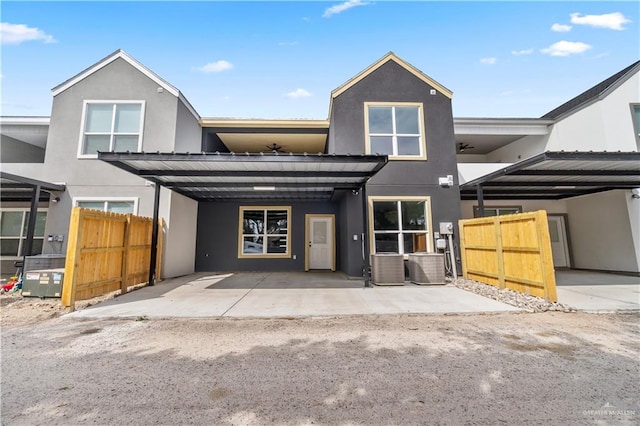 view of front of house featuring central AC unit, fence, an attached carport, and stucco siding