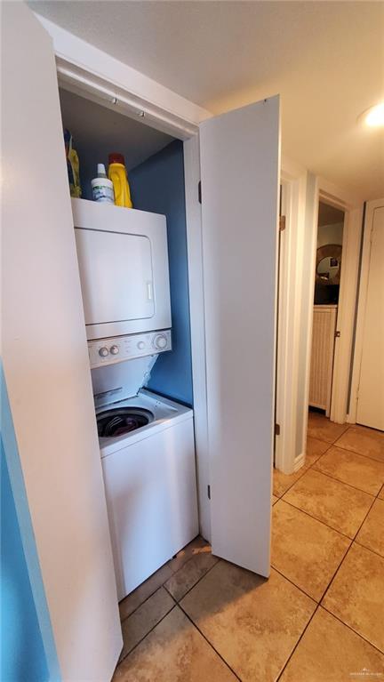 3113 Laguna Blvd Unit 219, South Padre Island, TX 78597 - laundry room featuring stacked washing machine and dryer and light tile patterned floors