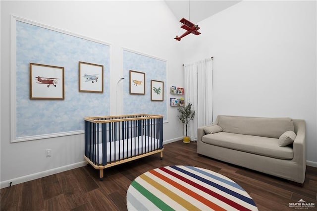 bedroom with a nursery area, dark hardwood / wood-style floors, and lofted ceiling