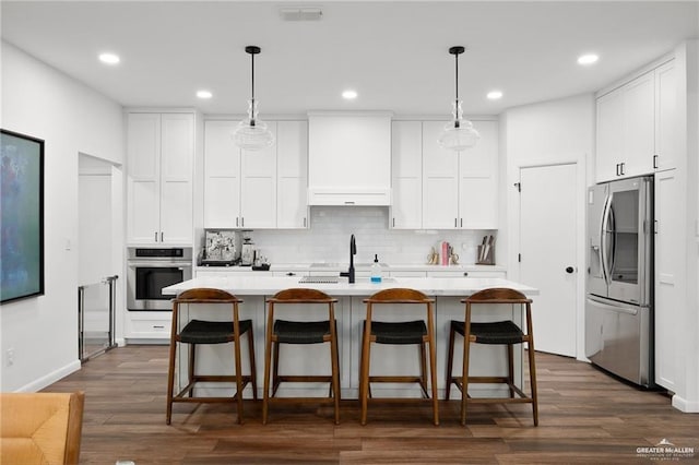 kitchen with white cabinetry, decorative light fixtures, an island with sink, and appliances with stainless steel finishes