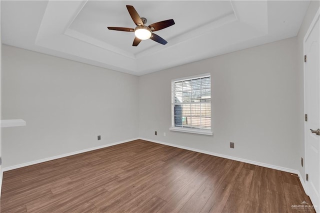 spare room with a raised ceiling, hardwood / wood-style flooring, and ceiling fan