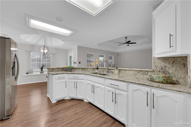 kitchen featuring stainless steel fridge with ice dispenser, decorative light fixtures, white cabinetry, sink, and kitchen peninsula