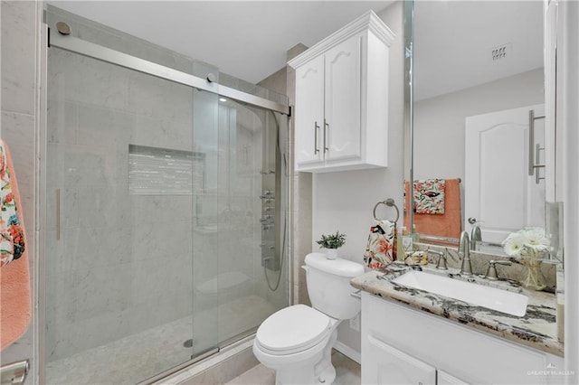 bathroom featuring vanity, a shower with door, and toilet