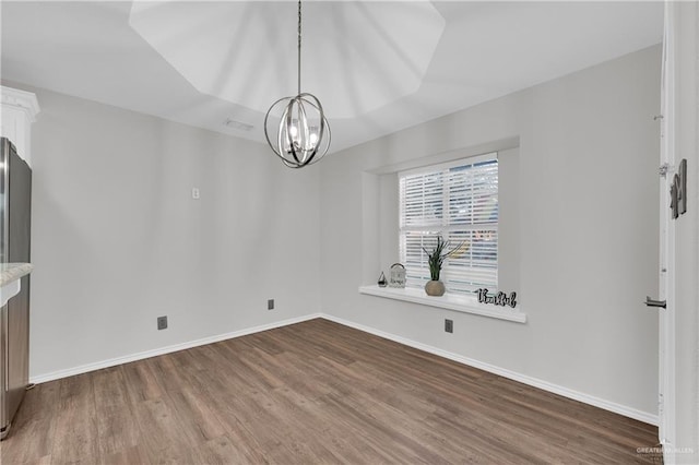 unfurnished dining area featuring wood-type flooring and an inviting chandelier