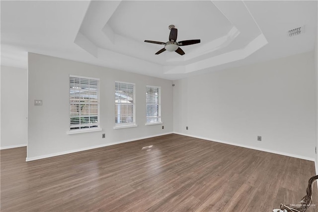 spare room with a raised ceiling, wood-type flooring, and ceiling fan