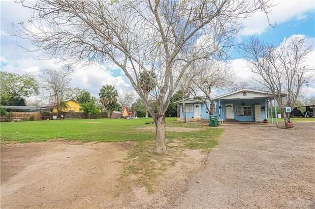 view of yard with driveway, fence, a carport, and a porch
