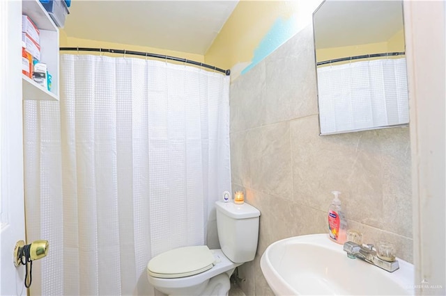 bathroom featuring toilet, tile walls, a sink, and curtained shower