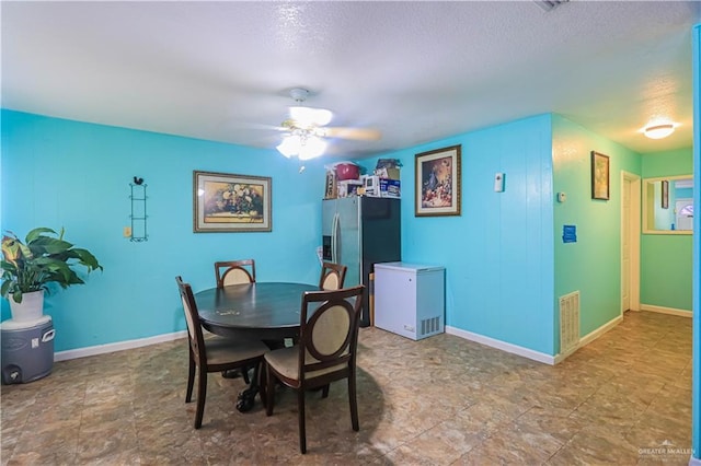 dining room with a ceiling fan, visible vents, a textured ceiling, and baseboards