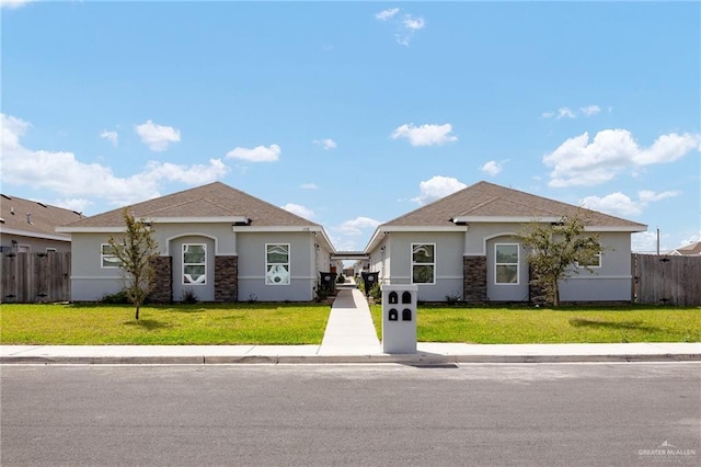 view of front of home with stone siding, stucco siding, a front yard, and fence