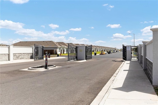 view of road with a gate, sidewalks, street lighting, a gated entry, and a residential view