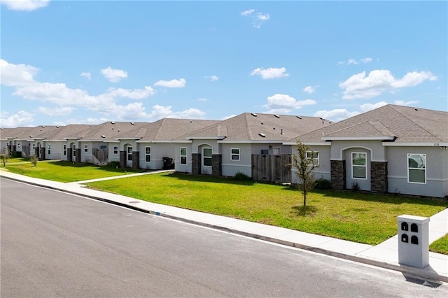 view of front of home featuring stone siding, stucco siding, a residential view, and a front lawn