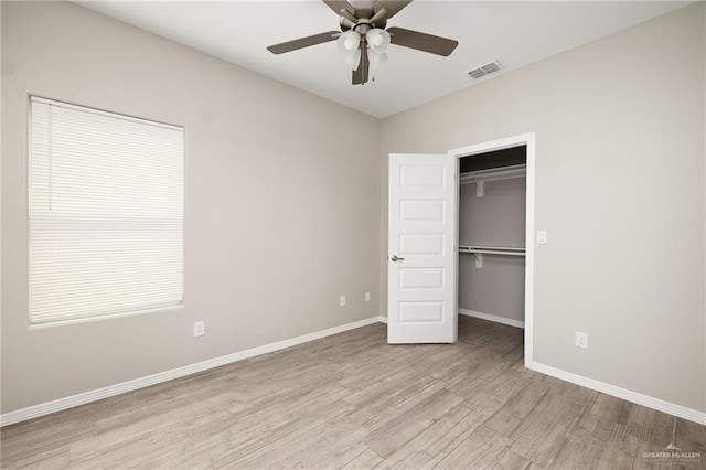 unfurnished bedroom with visible vents, baseboards, wood finished floors, and a spacious closet