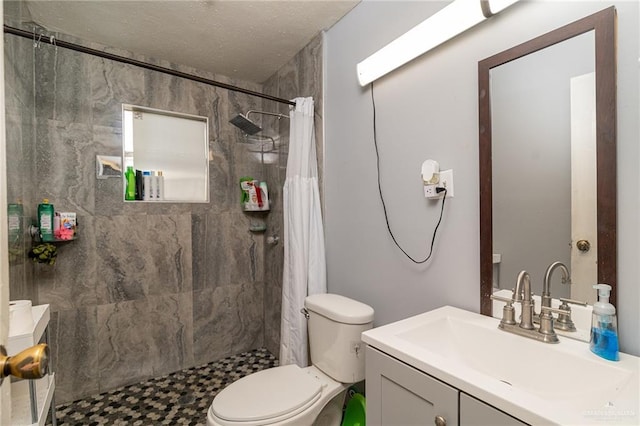 bathroom with a tile shower, vanity, and toilet