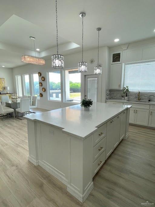 kitchen with light countertops, light wood-type flooring, white cabinets, and a kitchen island