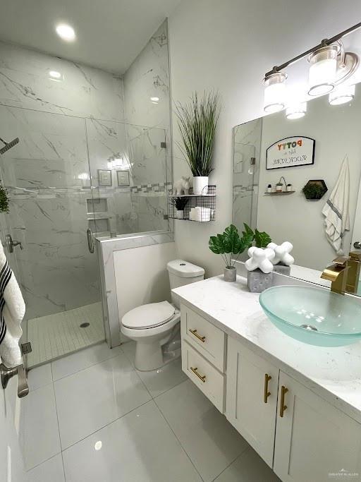 bathroom featuring toilet, a marble finish shower, and vanity